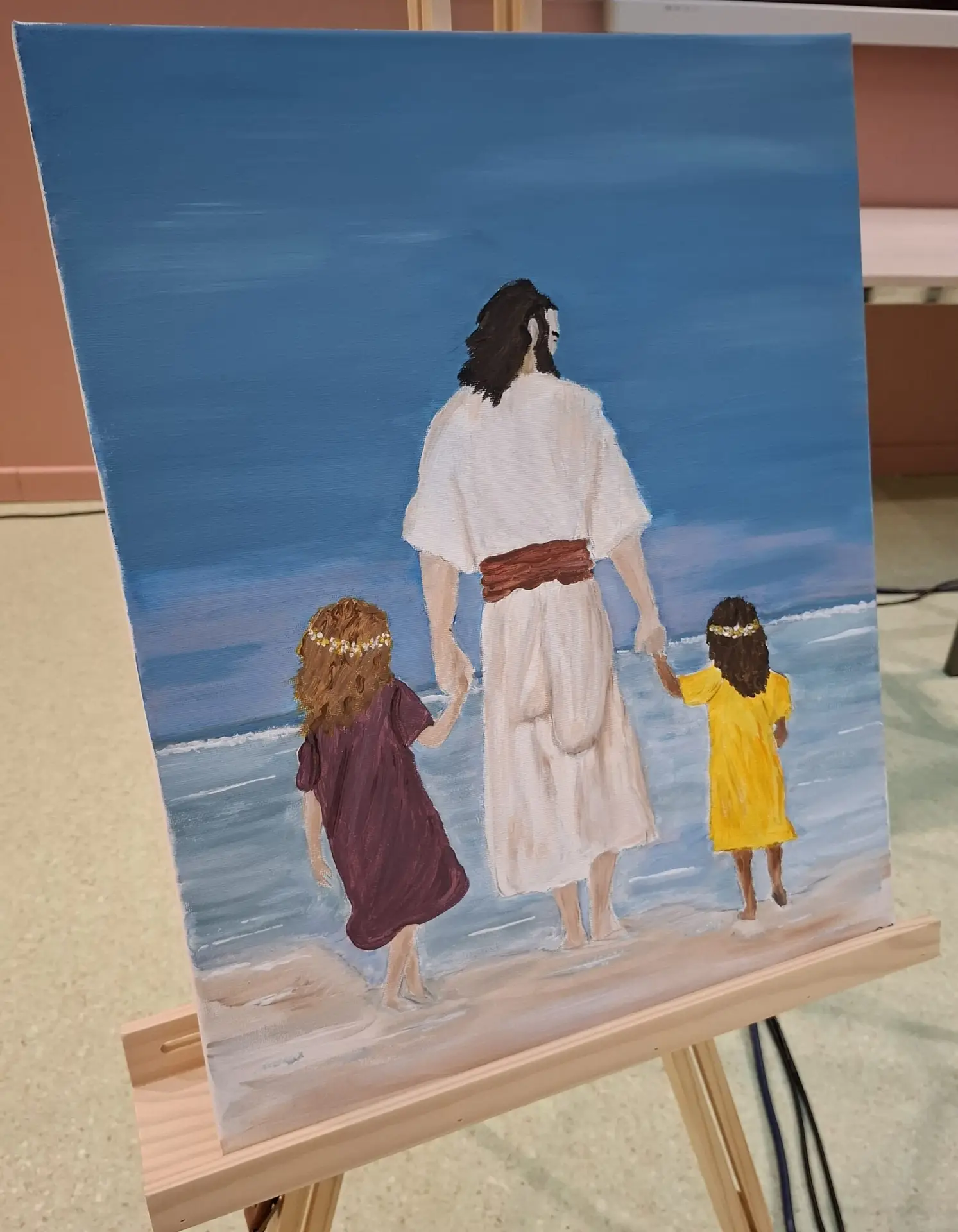 Schilderij van Jezus die met twee kinderen aan de hand door de branding loopt